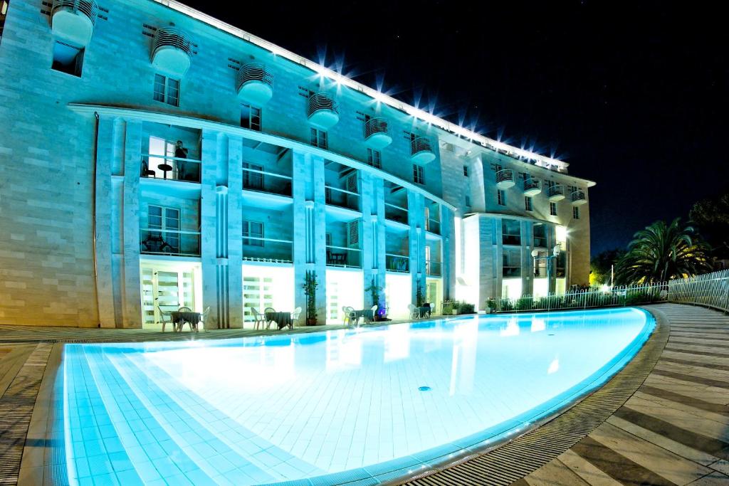 a large building with a large swimming pool at night at Onda Marina Residence Rta in Marina di Pietrasanta