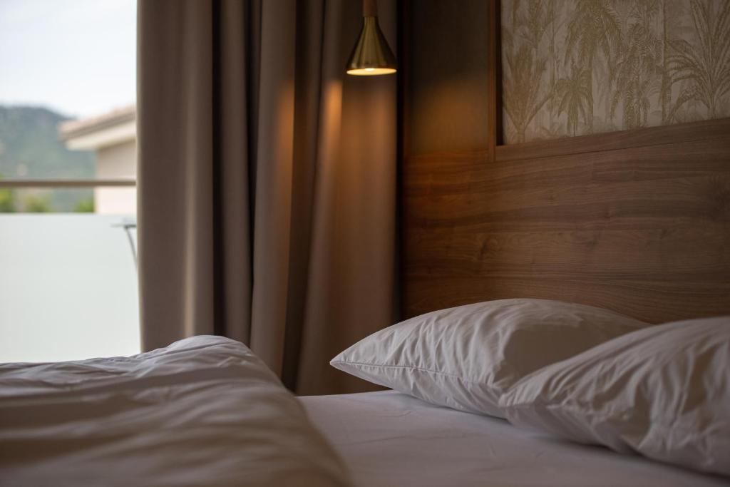 a bed with a wooden headboard and white pillows at Astra Sarti Luxury Suites in Sarti