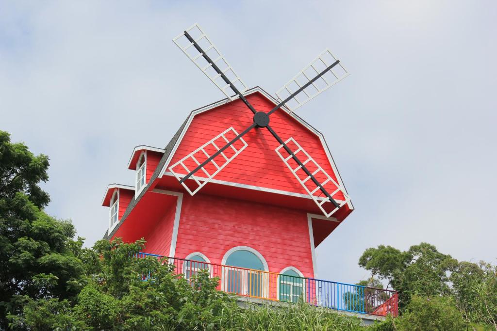 um moinho de vento vermelho no topo de algumas árvores em 綠意山莊 Greenforest em Yuanli
