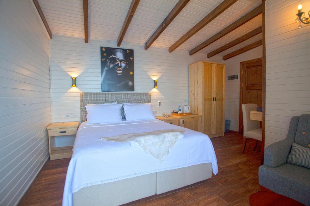 a bedroom with a large white bed and a chair at Sunset Villa Hotel in Kaş