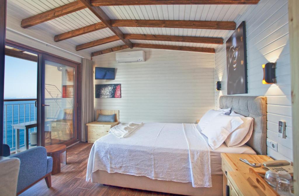 a bedroom with a bed and a large window at Sunset Villa Hotel in Kaş