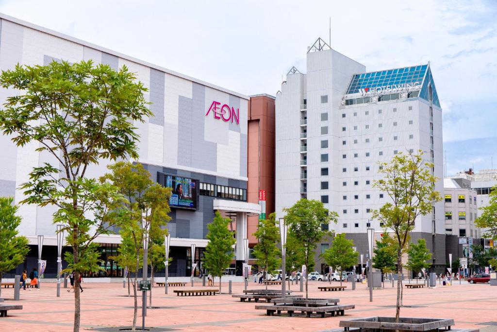 un gruppo di edifici in una città con panchine di Hotel Wing International Asahikawa Ekimae a Asahikawa