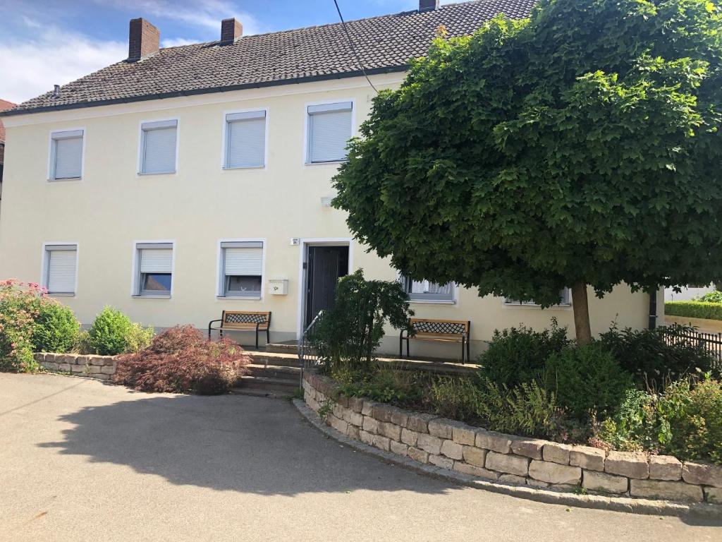 une grande maison blanche avec des bancs devant elle dans l'établissement Bauernhaus am Limes, à Altmannstein