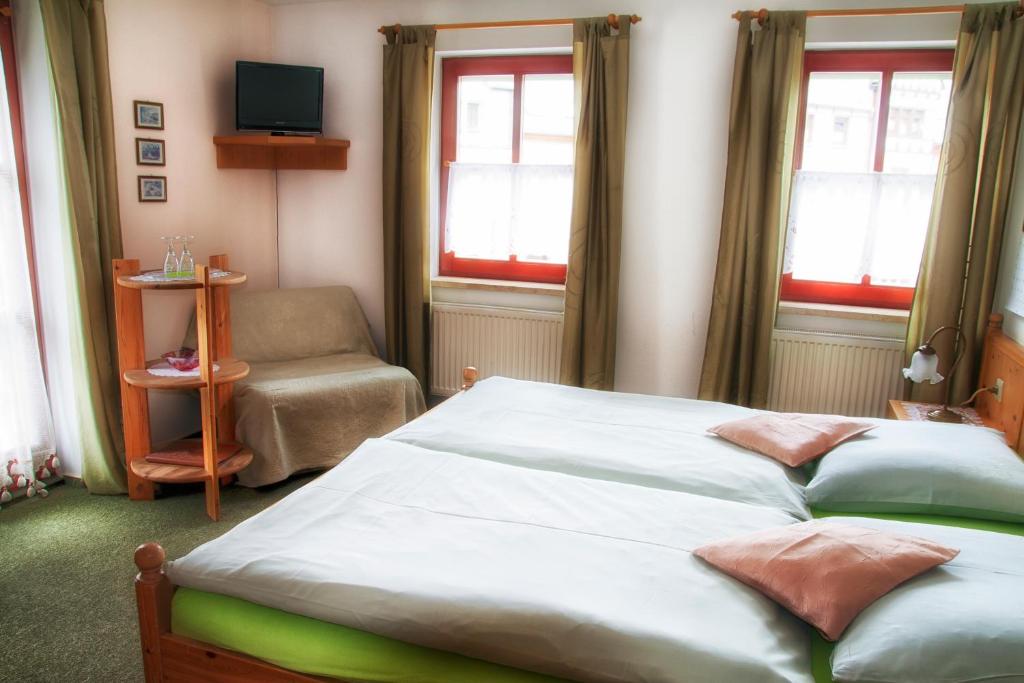 a bedroom with a bed and a chair and windows at Frühstücks Pension Zum Postillion in Klingenthal