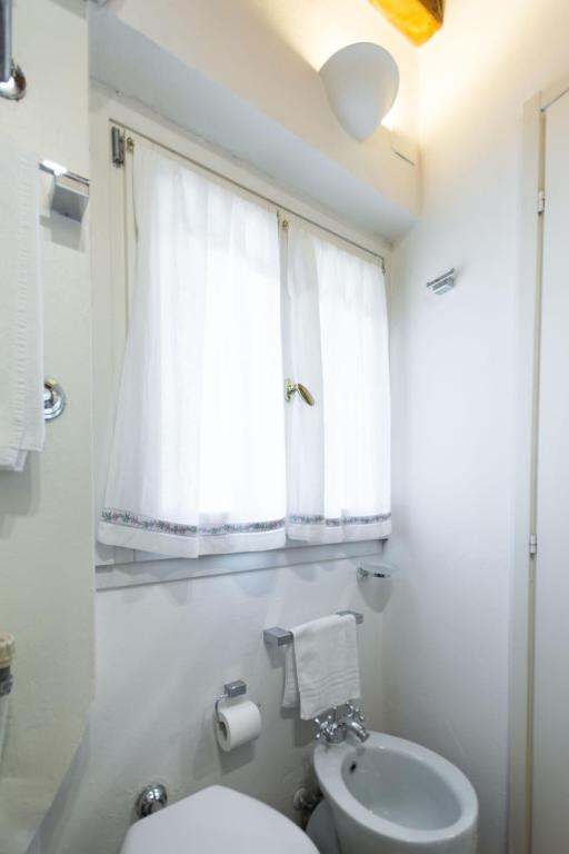 biała łazienka z toaletą i oknem w obiekcie TICINESE 59 APARTMENT w Mediolanie