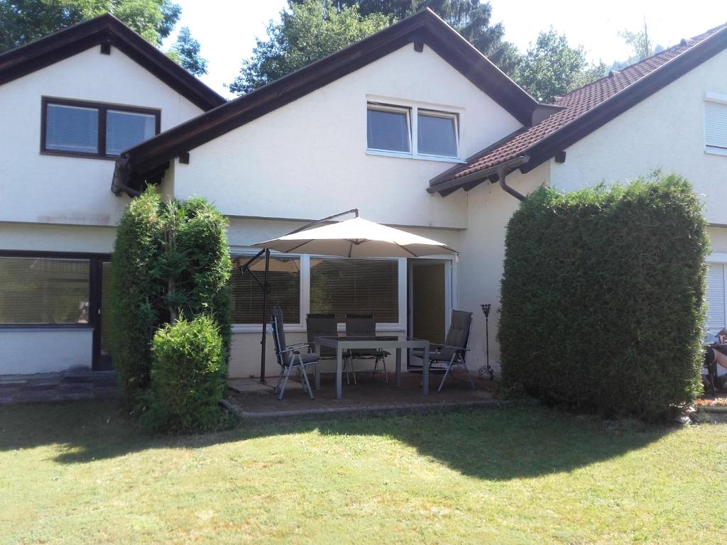 a white house with a table and an umbrella at Ferienhaus Döbriach am Millstätter See in Döbriach