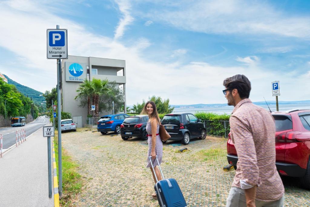 a man and a woman with a suitcase at a gas station at Hotel Miramare - Adults Only in Trieste