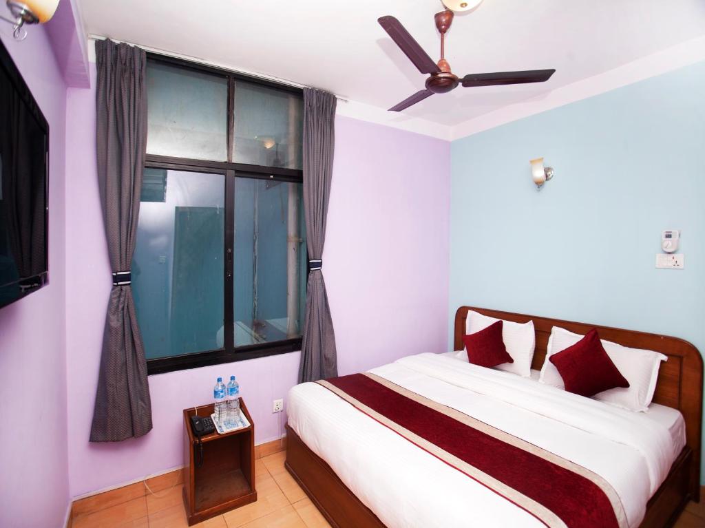 a bedroom with a bed with a ceiling fan and a window at Allied Hotel in Bālāju