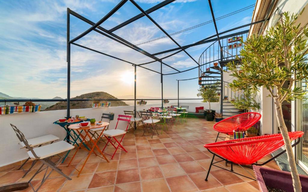 a balcony with red chairs and tables on a building at Boutique Hotel El Olivar in Mojácar