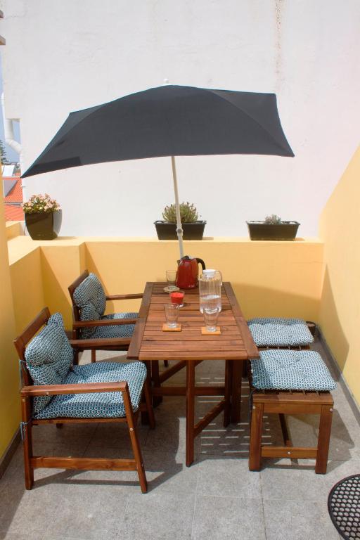 a wooden table with chairs and an umbrella at Friendly Peniche Apartment in Peniche