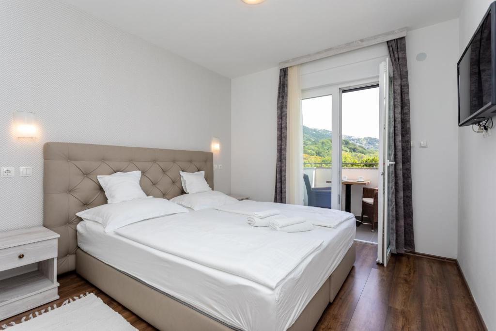 sypialnia z dużym białym łóżkiem i oknem w obiekcie Bed & Breakfast Došen V w Bašce