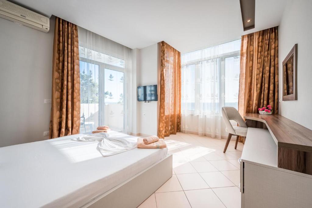 een slaapkamer met een bed, een bureau en een raam bij Hotel Kamomil in Durrës