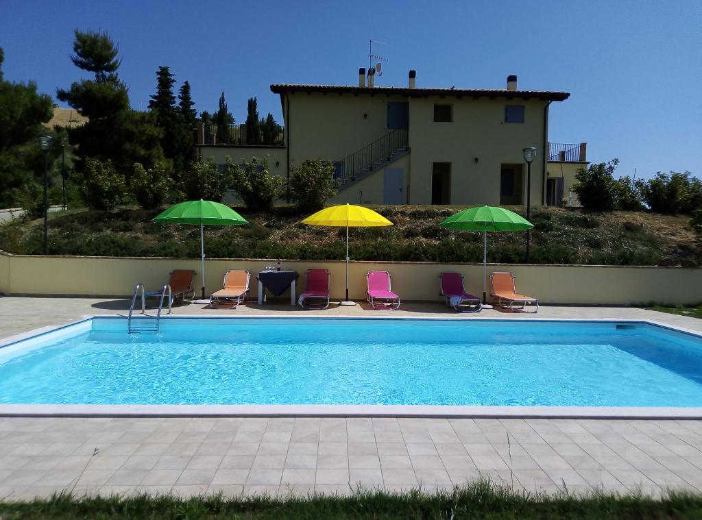 a swimming pool with chairs and umbrellas in front of a house at Agriturismo Terra dei Falchi in Castilenti