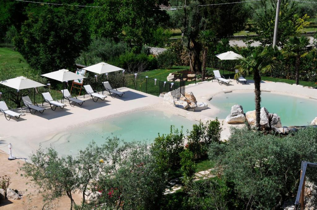 einen Blick über einen Pool mit Stühlen und Sonnenschirmen in der Unterkunft Hotel La Grotte in San Donato Val di Comino