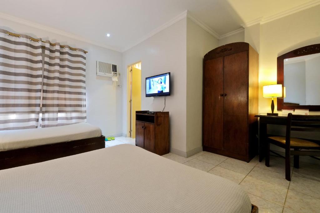 a bedroom with a bed and a desk and a television at Palazzo Pensionne in Cebu City