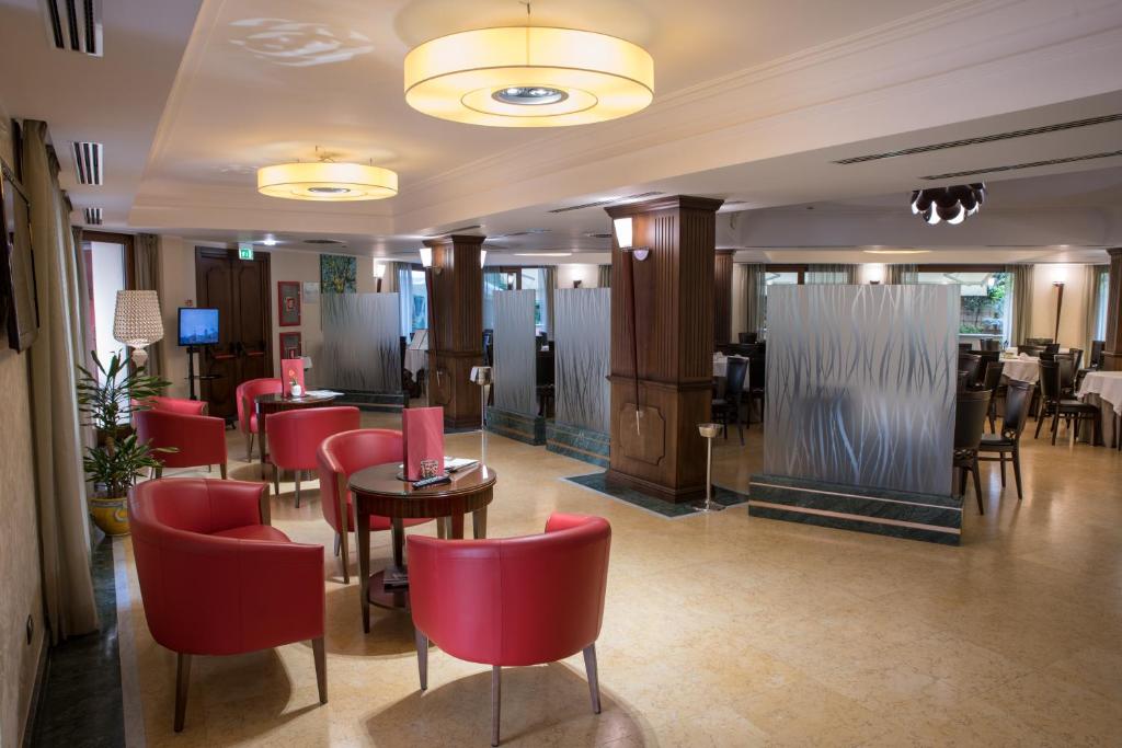 a restaurant with red chairs and tables in a room at Artemis Hotel in Cefalù