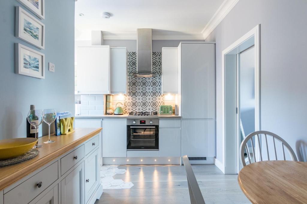 uma cozinha com armários brancos e uma mesa com uma sala de jantar em BlueNess, City Centre Luxury Apartment em Inverness