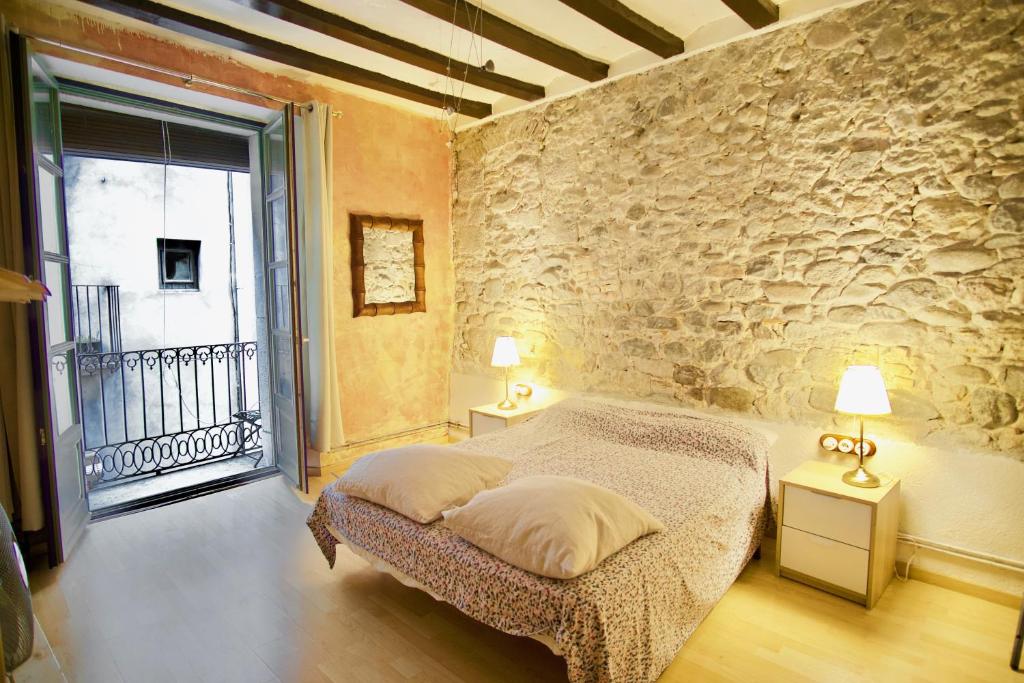 1 dormitorio con cama y pared de piedra en La Lleona Apartment en Girona