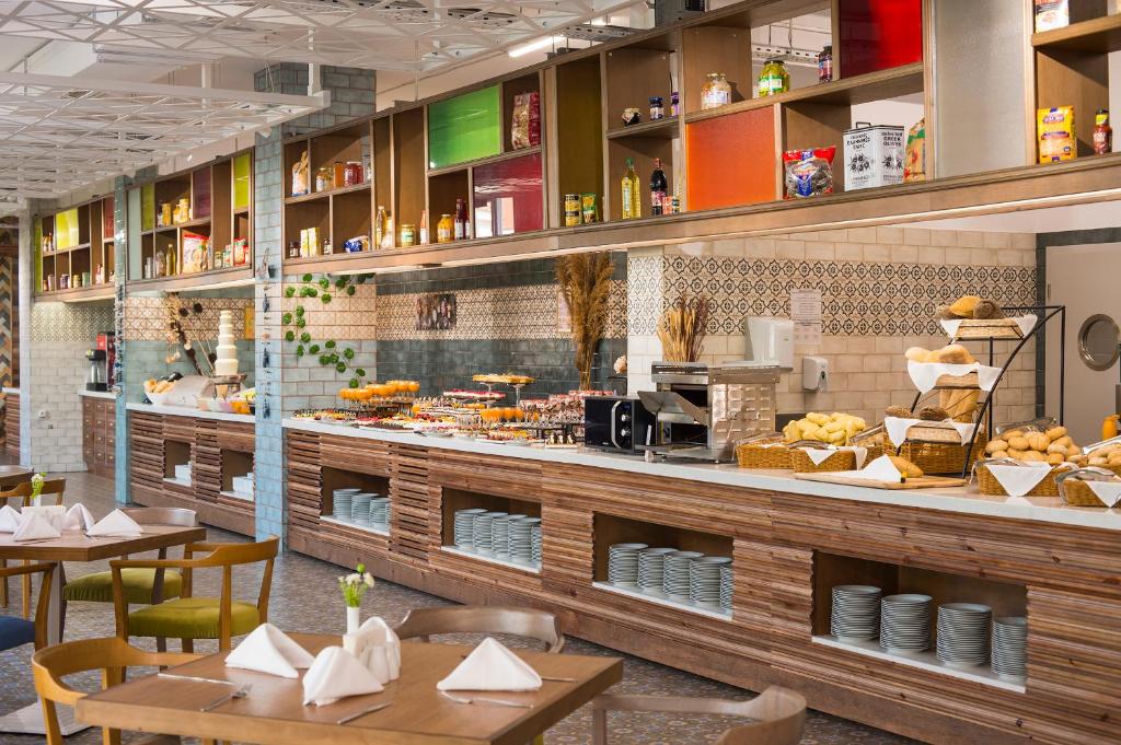 a restaurant with tables and a counter with food at Sunrise Blue Magic Resort - All Inclusive in Obzor