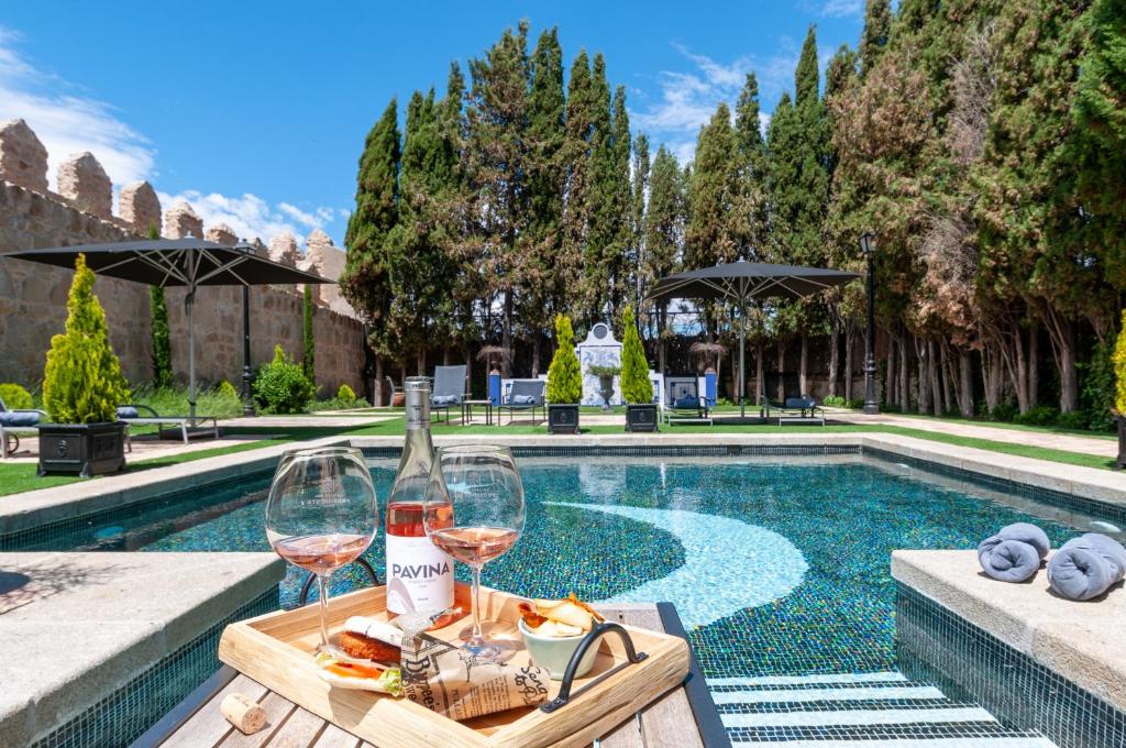 uma mesa com dois copos de vinho ao lado de uma piscina em La Casa del Presidente em Ávila