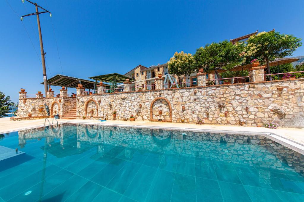 a large swimming pool in front of a stone wall at Hotel "SAN SAENA " in Vlorë