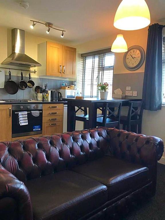 a living room with a leather couch in a kitchen at Coleman Apartment in Wolverhampton