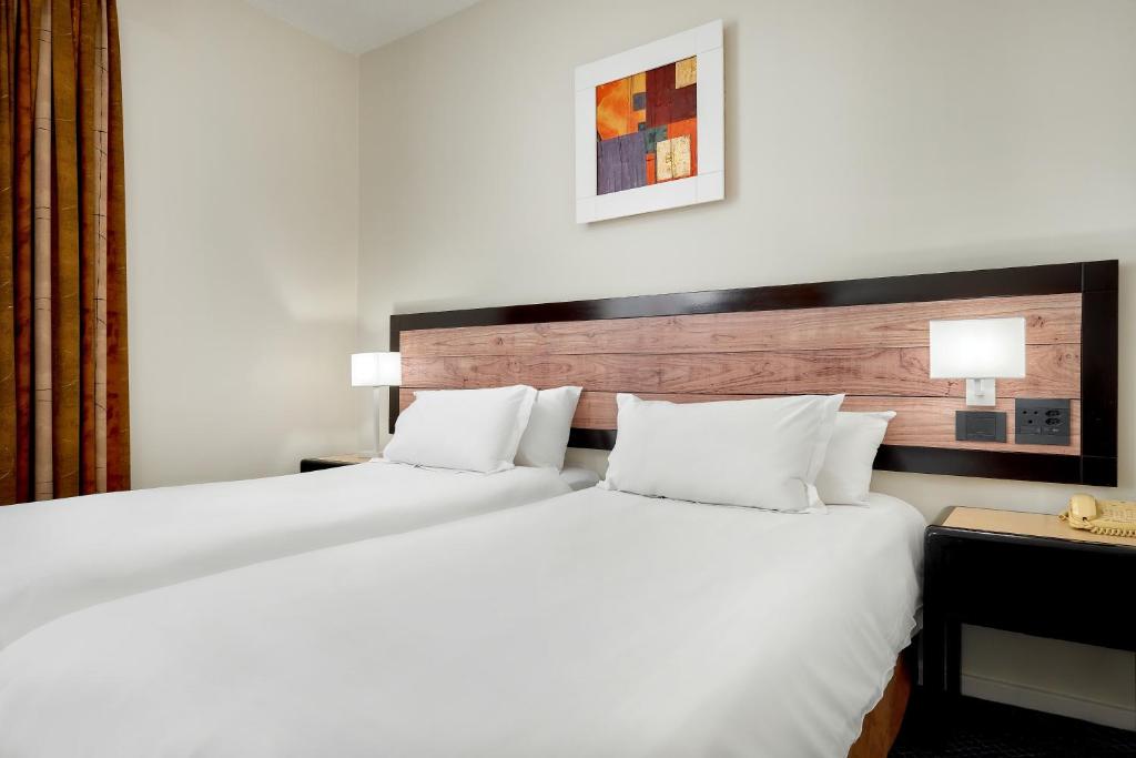 a hotel room with a large bed with white pillows at ANEW Hotel Parktonian Johannesburg in Johannesburg