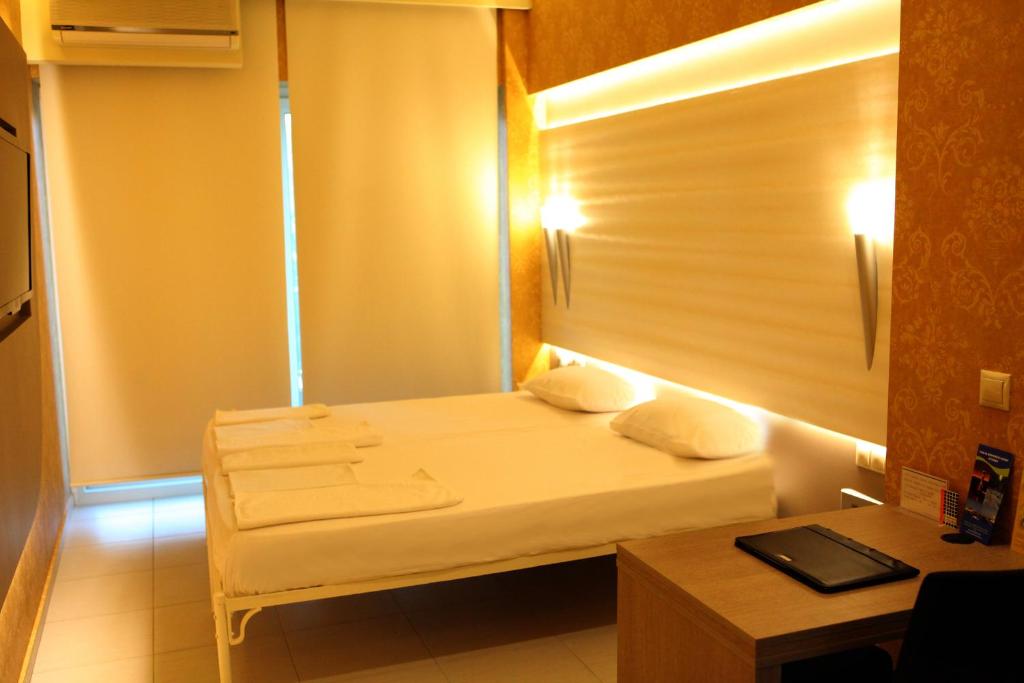 ソウダにあるOneiro Suitesのベッドとデスクが備わる小さな客室です。