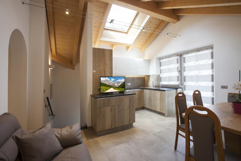 a kitchen with a couch and a tv in a room at Fiemme Home Mountain Apartment in Tesero