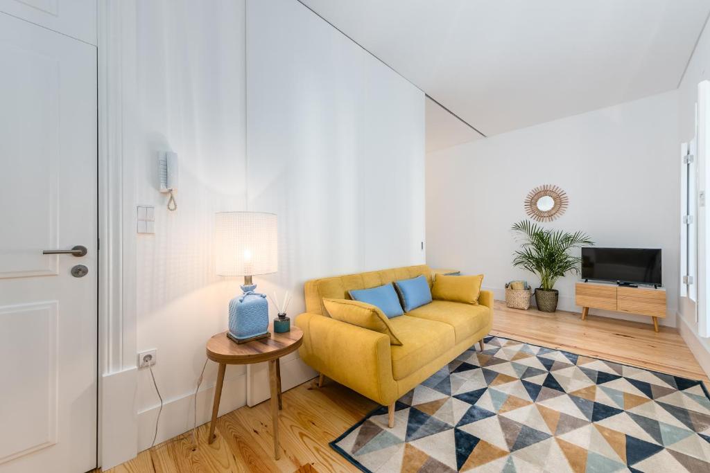 a living room with a yellow chair and a table at Porto Belo Sao Bento Apartment in Porto