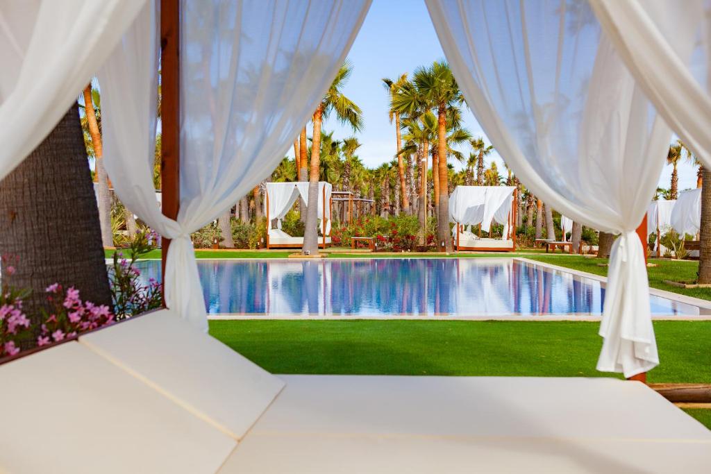 een kamer met een bed en gordijnen en uitzicht op een zwembad bij VidaMar Resort Hotel Algarve in Albufeira