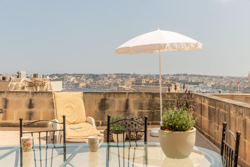 a patio with an umbrella and a table and chairs at Valletta Penthouse in Valletta