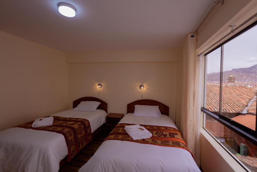 dwa łóżka w pokoju z oknem w obiekcie Hawka Inka Hostal - Cusco w Cuzco