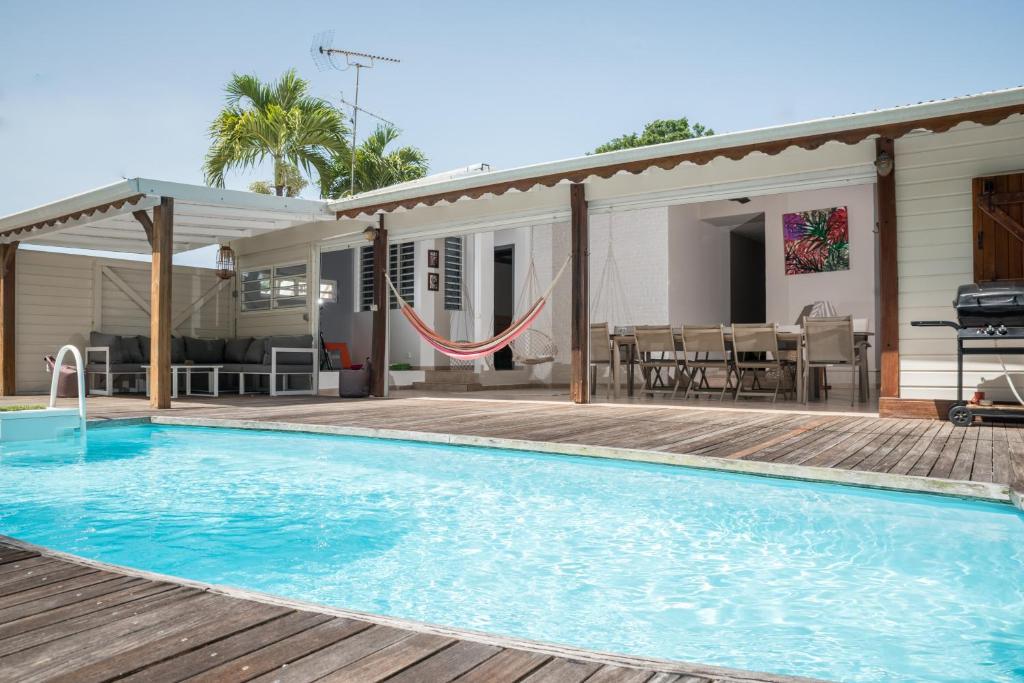 a swimming pool with a hammock and a house at Villa Cosy - Grande capacité avec piscine in Le Gosier