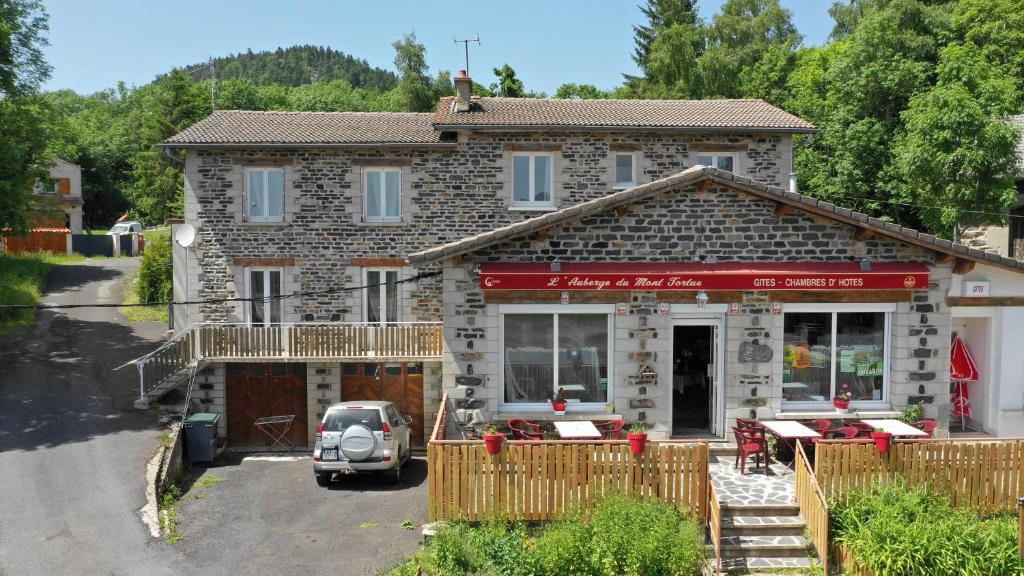 uma casa com um carro estacionado em frente em Auberge du Mont Tortue em Champclause