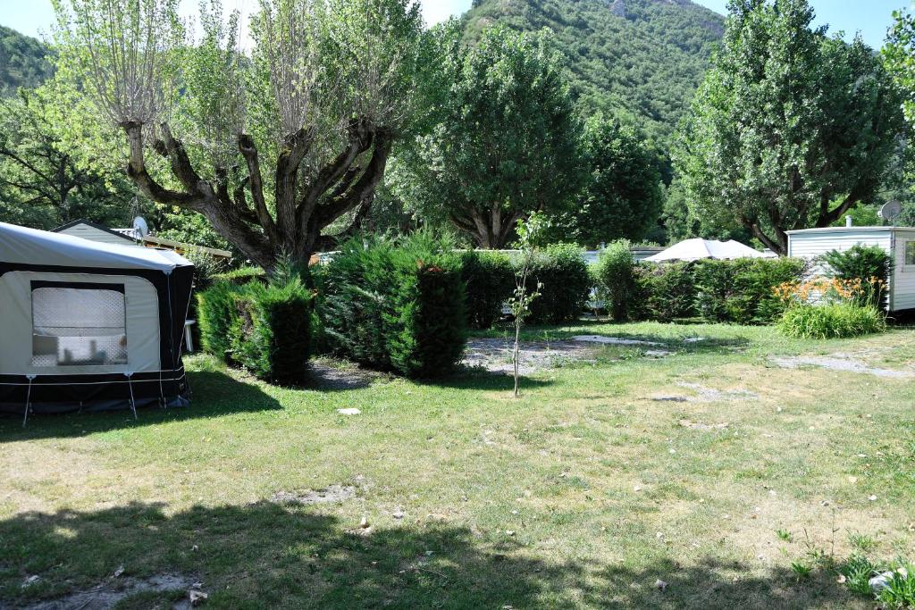 une tente dans une cour avec un arbre et des buissons dans l&#39;établissement Camping du Bourg, à Digne-Les-Bains