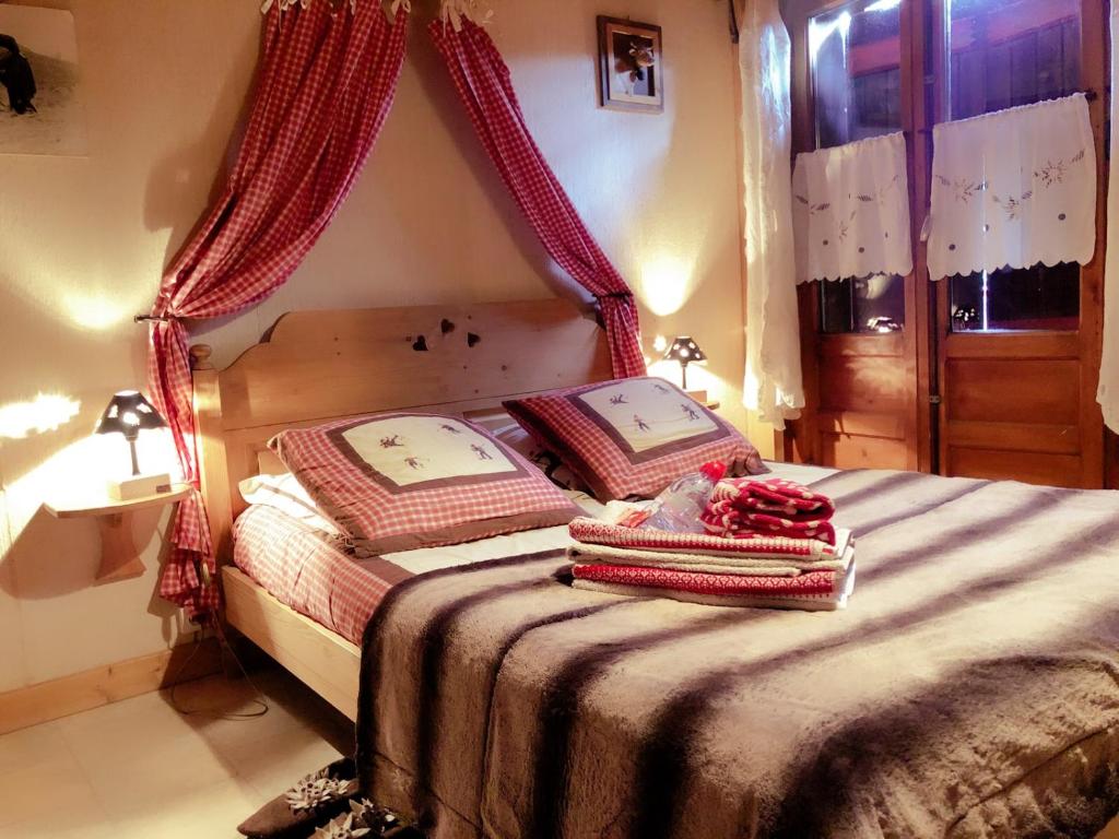 モントリオンにあるChalet Génépiのベッドルーム1室(赤いカーテンと毛布付きのベッド1台付)