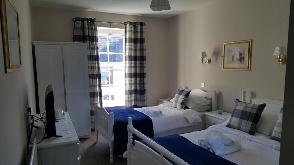 a bedroom with two beds and a window at Central Bar Guesthouse in Cushendall