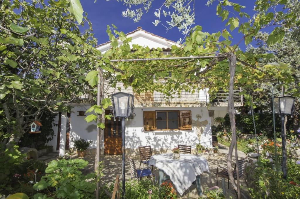 a white house with a table and chairs in the yard at Rasopasno 2 in Malinska