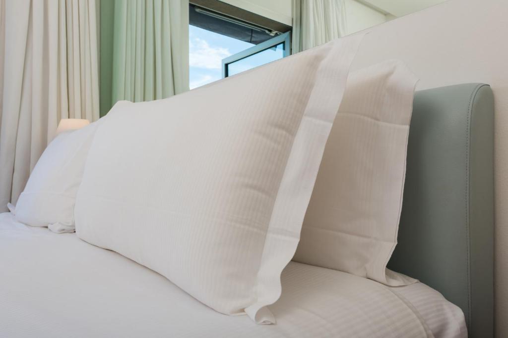 a bed with white pillows on it with a window at Hotel Miramare - Adults Only in Trieste