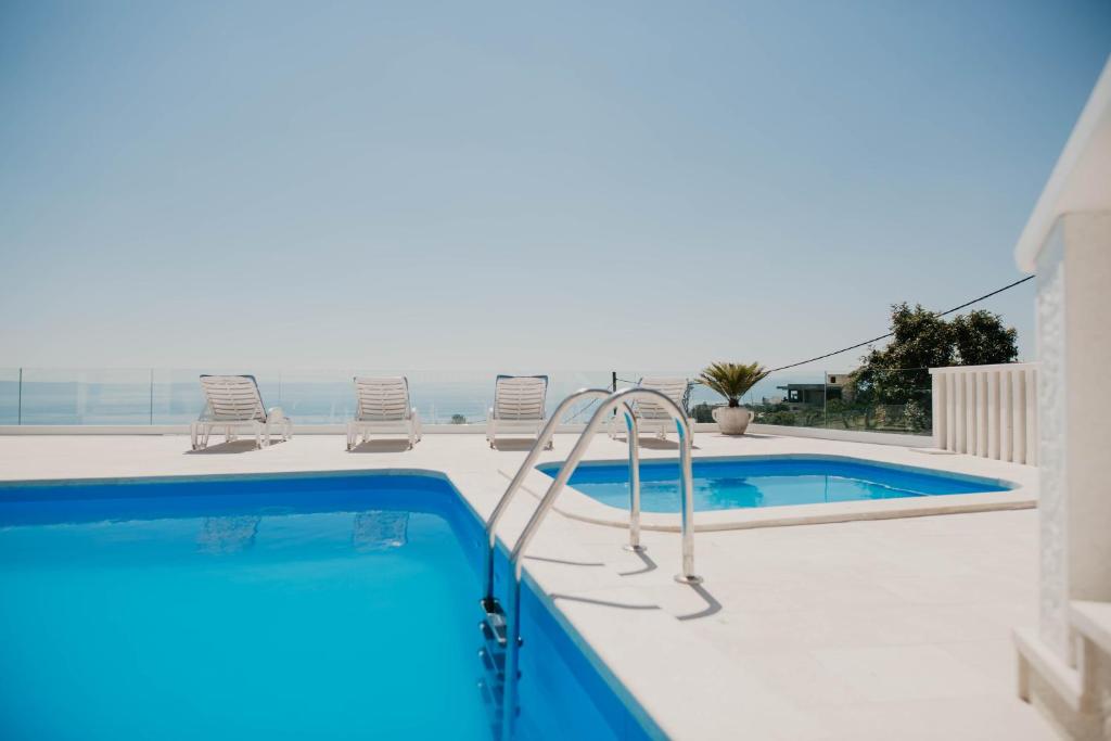 a swimming pool with two chairs and a swimming pooliterator at Villa Hills in Makarska