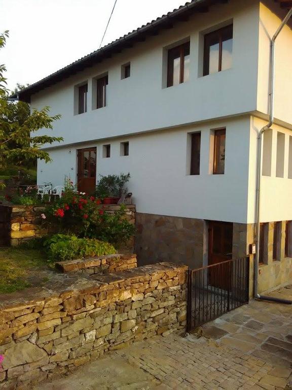 a white house with a stone wall in front of it at Fenix Rooms in Arbanasi
