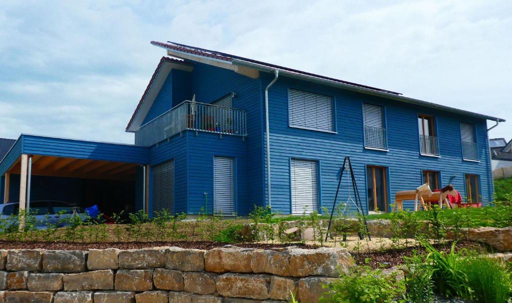a blue house with a stone wall in front of it at Ferienwohnung Bodensee Bullerbü in Eigeltingen