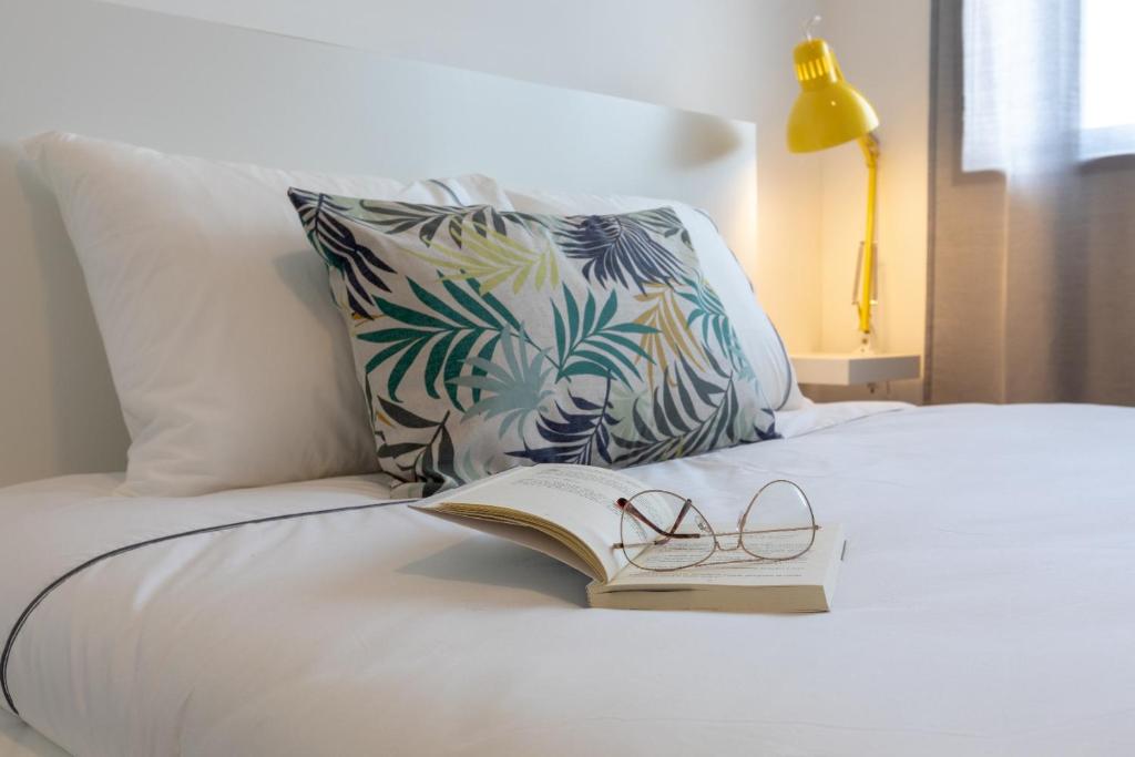 un libro y gafas en una cama con almohada en Buddies Family Room, en Aveiro