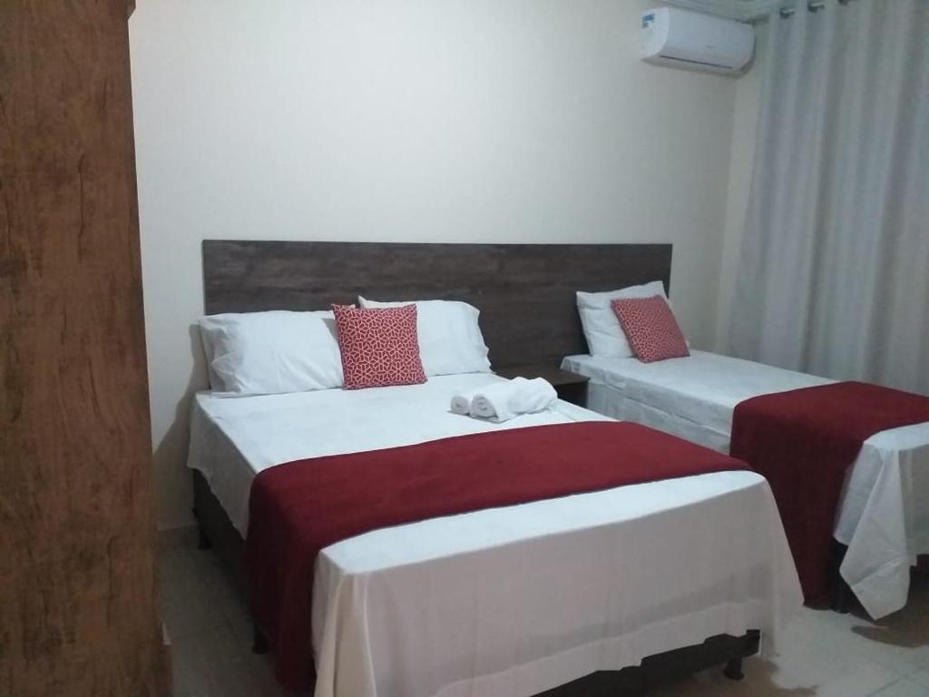 a bedroom with two beds with red and white sheets at CALDAS NOVAS RESIDENCE - Inclui um ingresso por pessoa em Parque Aquático e temos HOT PARK a preço promocional in Caldas Novas