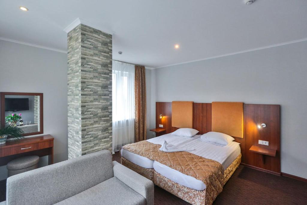 um quarto com uma cama, uma cadeira e um sofá em Hotel Nastup em Dombay
