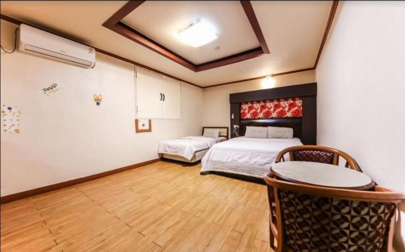 a bedroom with two beds and a table in it at Prince Hotel in Gwangju