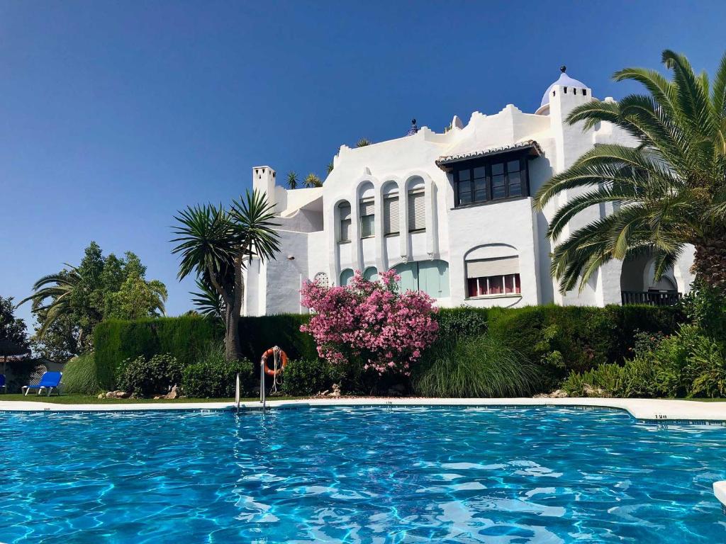 a white house with a swimming pool in front of it at Bright apartment 300m from the beach in Sitio de Calahonda