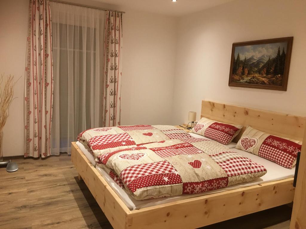 um quarto com uma cama de madeira com colchas vermelhas e brancas em Urlaub am Moarbauerhof em Mühlen