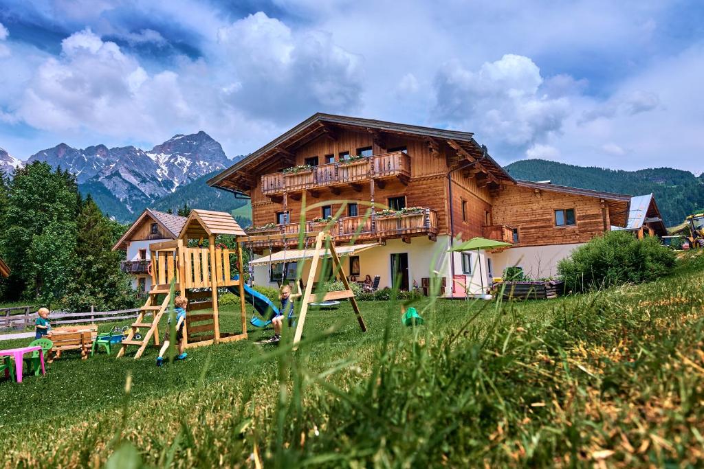 una casa de madera con un parque infantil delante de ella en Haus Obermühle, en Maria Alm am Steinernen Meer